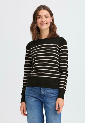 Svart og beige stripete genser med rund hals, lange ermer og ribbet hem. Brukt over blå jeans. Myk tekstur og tettsittende design.