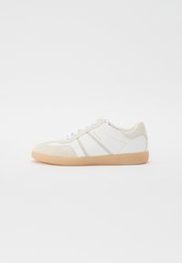 Sneakers bianche con accenti in suede beige, suola piatta beige e strisce grigie sottili. Le stringhe sono bianche. Design semplice e a profilo basso.