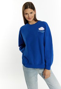 Felpa blu in cotone, con scollo rotondo, spalle drop e un design di nuvola ricamato con testo sul petto.
