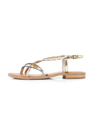 Sandali piatti metallici oro e argento con dettagli intrecciati e fibbia su un plantare in pelle marrone e un tacco in legno stratificato.