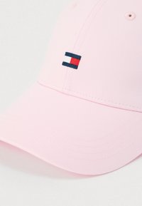 Ροζ καπέλο με καμπύλη γείσο, κατασκευασμένο από υφασμάτινο υλικό με υφή. Διαθέτει μικρό λογότυπο σε μπλε ναυτικό, άσπρο και κόκκινο στο μπροστινό μέρος. Κλασικός σχεδιασμός.