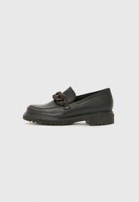 Mocassins en cuir noir avec une semelle épaisse, présentant un accent décoratif en chaîne à l'avant et une finition lisse sur l'ensemble.