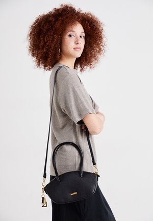 Sac à main en cuir noir grainé avec deux poignées, quincaillerie dorée et bandoulière amovible. Forme arrondie, design minimaliste et fermoir sécurisé.