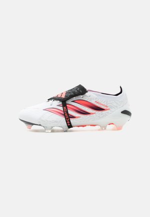 Witte Adidas Predator voetbalschoen met roze en zwarte accenten, veterhoes en gevormde noppen op de zool voor grip.