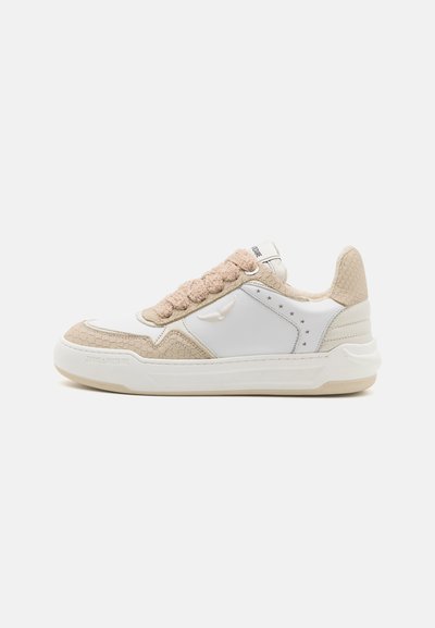White sneakers featuring a textured beige accent, braided tongue, and subtle star details. Rubber sole with a smooth finish.