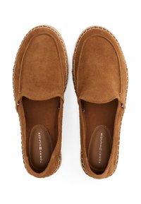 Barna velúr slip-on cipők textúrált felsőrésszel, varrott szélekkel és márkás talppal. Minimalista kiegészítők és egyszerű, áramvonalas dizájn jellemzi.