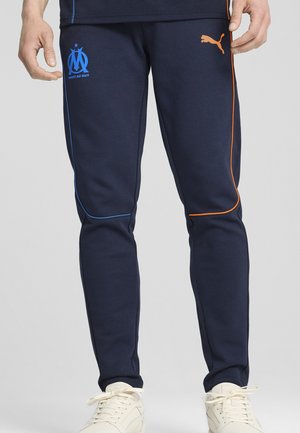 Pantalones deportivos de la marina con un diseño ajustado, acentos laterales en azul y naranja, y el logo de Marsella. Fabricados en tejido suave, cuentan con puños elásticos.