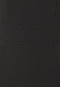 Černý oděv s hladkým, texturovaným materiálem. Vyznačuje se jasně definovaným pasem a minimalistickým designem bez viditelných vzorů nebo kovových prvků.