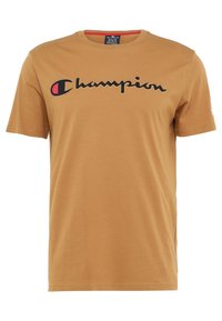 Hnědé bavlněné tričko s černým logem "Champion" na hrudi a malým červeným akcentem na levém rukávu. Krátké rukávy, klasický kulatý výstřih.
