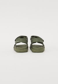 Green sandals featuring adjustable straps, open back design, textured footbed, and "WATER FRIENDLY" branding on the side.