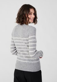 Grijs gestreepte trui met een zachte, gebreide textuur, geribbelde onderrand en witte horizontale strepen. Achteraanzicht toont een ronde halslijn en een slanke pasvorm.