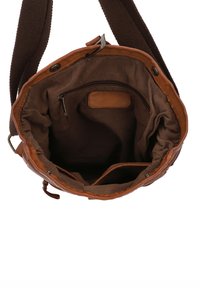 Brown leather and fabric tote bag with a soft, textured interior, features a zippered pocket and two open compartments.