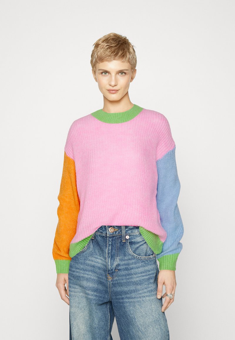 Pull en tricot avec un motif en blocs rose, orange, bleu et vert. Texture côtelée, col rond et coupe décontractée.