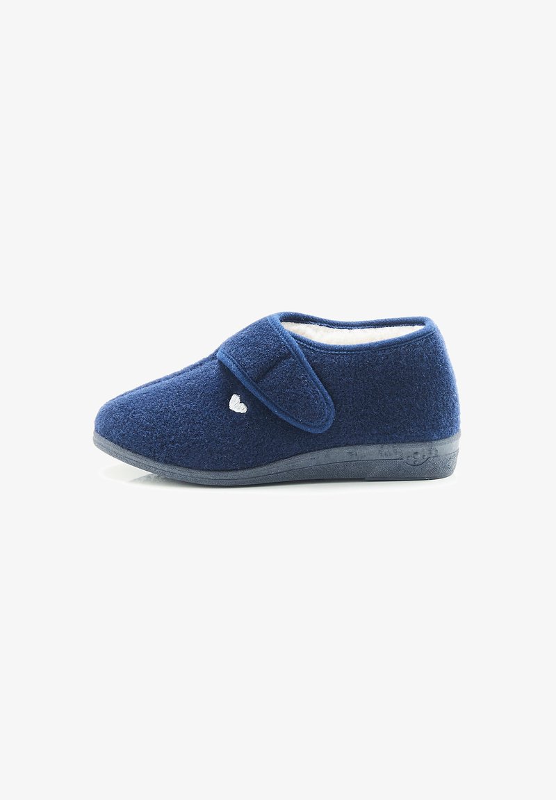 Zapatilla de color azul marino hecha de suave forro polar, con una correa de Velcro y un acento en forma de corazón blanco, con una suela de goma texturizada para mayor agarre.
