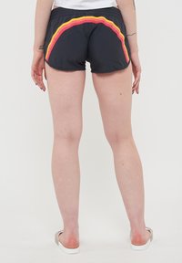 Pantaloni sportivi neri con una fascia curva rossa e gialla lungo l'orlo posteriore, dotati di una vita elastica e realizzati in materiale leggero.