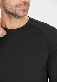 Black long-sleeve shirt with a round neckline and raglan sleeves, featuring a smooth texture and minimal stitching details.
