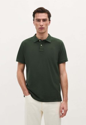 Camisa polo verde oscuro de algodón con cuello, dos botones y mangas cortas. Presenta un logotipo sutil y una textura lisa.