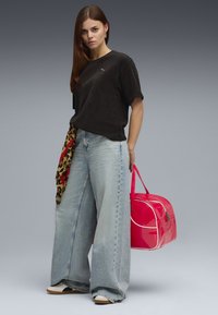 Zwarte geribbelde top met korte mouwen, oversized lichtblauwe jeans, rode en luipaardprint sjaal, roze lakhandtas met witte accenten en witte schoenen.