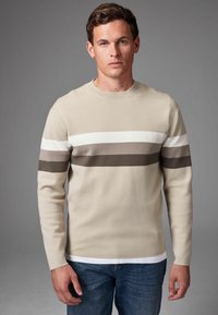 Suéter de punto beige con rayas horizontales en blanco, marrón y marrón oscuro; cuello redondo, mangas largas y un acabado texturizado.