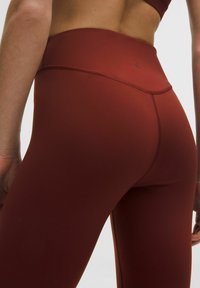 Bordeaux magas derékú leggings, rugalmas anyagból készült, sima textúrájú és minimális varrással, a derékon szorosan illeszkedve.