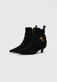Black suede ankle boots with a pointed toe, low kitten heel, and gold hardware accents, featuring a strap detail around the ankle.