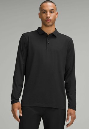 Black long-sleeve polo shirt made of smooth fabric with a collar and three-button placket. Features a relaxed fit and a straight hem.