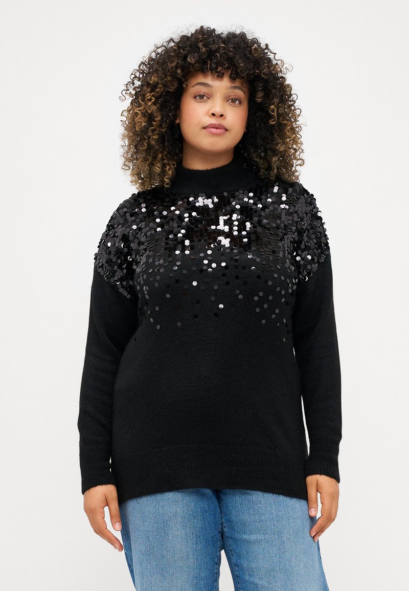 Juodas megztinis, pagamintas iš minkštos medžiagos, su blizgučiais dekoruota viršutine dalimi. Jis turi apvalų iškirpimą ir ribotos formos rankoves, yra laisvo silueto.