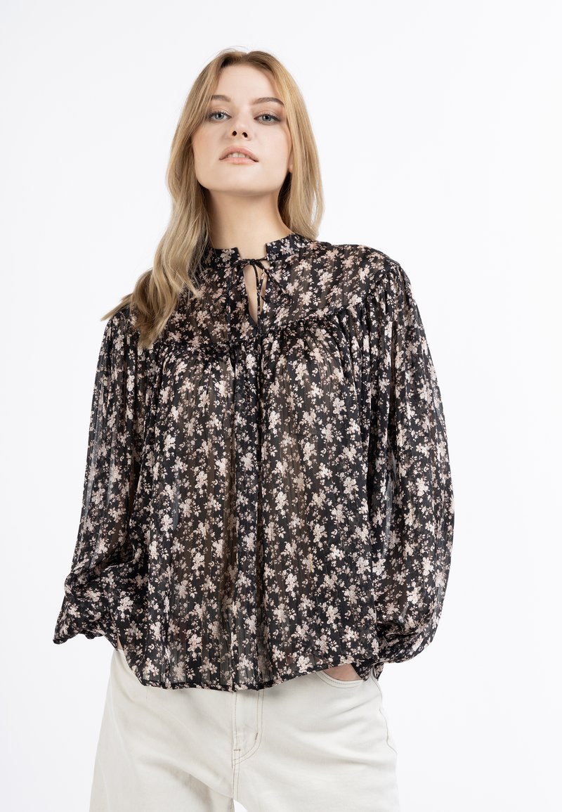 Blouse noire en voile avec imprimé floral, design plissé, col haut avec fermeture à nouer, et manches bouffantes. Tissu léger et texturé.