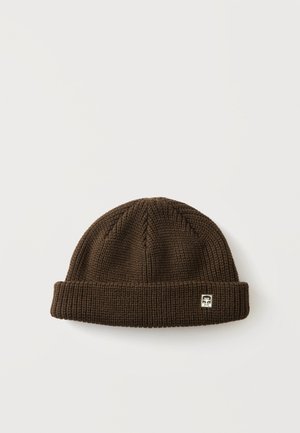 Cappello beanie lavorato a maglia marrone scuro con risvolto piegato e piccolo patch logo bianco e nero sul risvolto su sfondo uniforme.