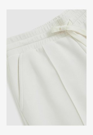 I pantaloni della tuta beige chiaro presentano una cintura elastica, un laccio regolabile, tasche laterali e pieghe sottili per una vestibilità confortevole.