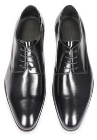 Chaussures de ville en cuir noir avec une finition brillante, bout pointu et système de laçage à cinq œillets. Comprend des détails de couture subtils le long des bords.