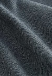Denim tkanina u tamnoplavoj boji s suptilnom tkane teksturom, koja prikazuje nabore koji ističu nježnost i fleksibilnost.