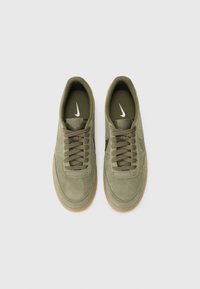 Oliwkowe zamszowe sneakersy z okrągłym noskiem, sznurowane, z gumową podeszwą. Z białym logo Nike po boku.
