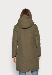 Olivgrön, vattenavvisande parka med huva, dragkedjestängning och sidofickor; knälång med rak skärning och rena linjer.