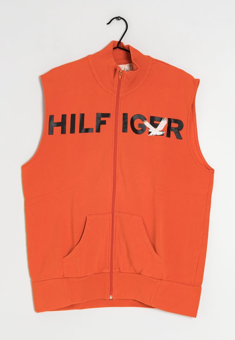 Orange ärmlös zip-up väst med svarta texten "HILF IG R" och en vit örn grafik, framfickor samt ribbad krage och nederkant.