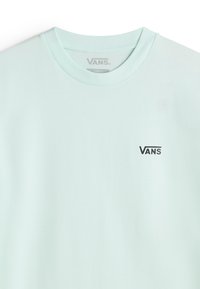 Vaalean mintunvihreä puuvillapaita, jossa on pyöreä kaula-aukko; vasemmassa rinnassa pieni musta "VANS"-logo. Tasainen rakenne, rento istuvuus.