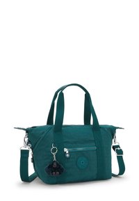 Teal bag made of textured fabric, featuring dual handles, a detachable shoulder strap, and a furry monkey keychain accent.