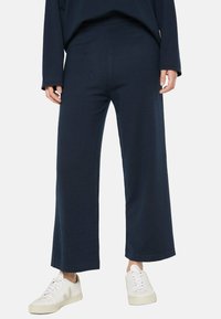 Navyweite Hose aus weichem Stoff, mit gerader Silhouette und elastischem Bund, kombiniert mit weißen Sneakers.