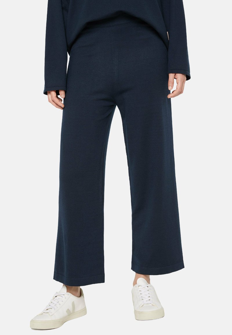 Navyweite Hose aus weichem Stoff, mit gerader Silhouette und elastischem Bund, kombiniert mit weißen Sneakers.