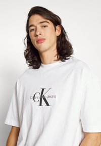 Calvin Klein Jeans MONOLOGO TEE UNISEX - Camiseta estampada - bright white