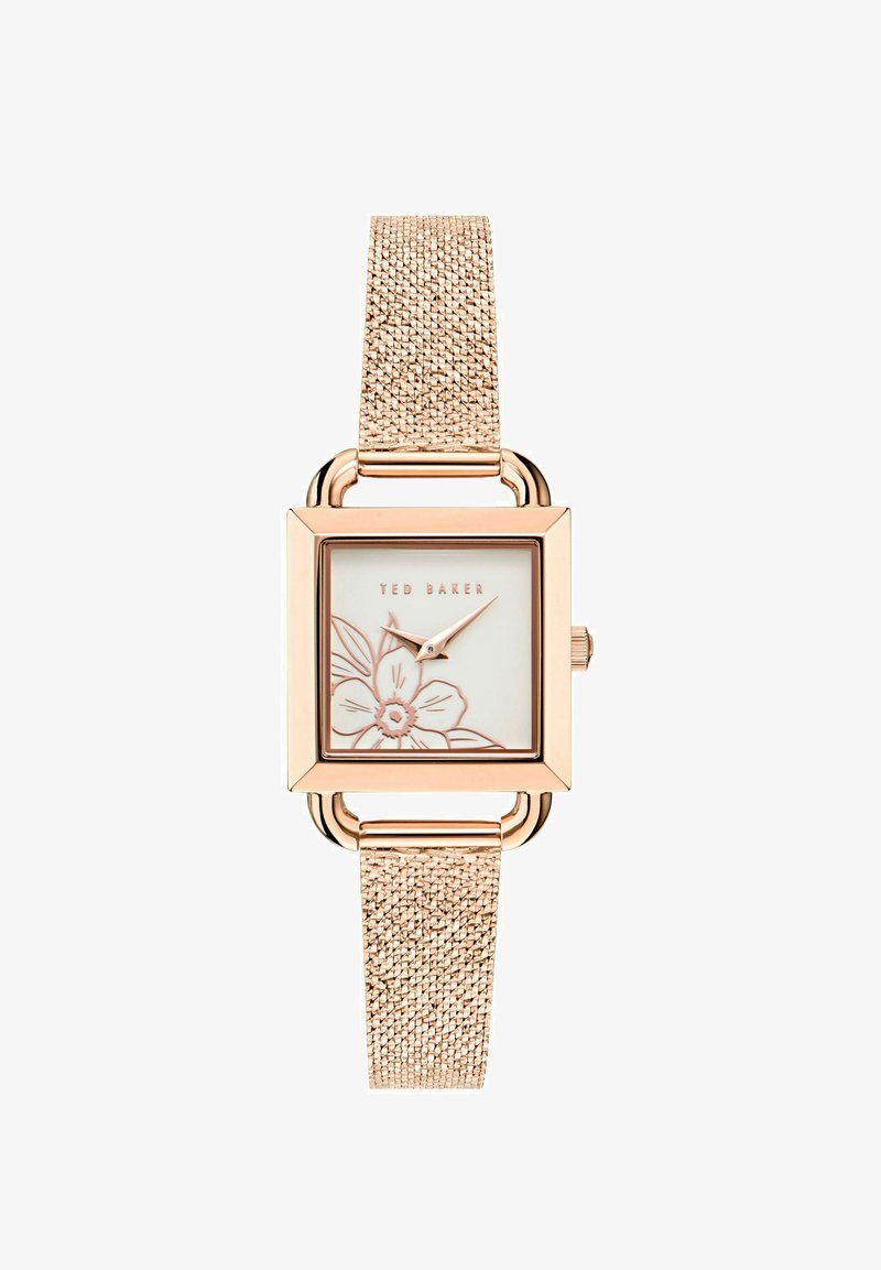 Rózsaarany négyzet alakú óra texturált fém szíjjal. Fehér számlapján virágmintázat és arany részletek találhatóak. A "Ted Baker" márkaneve kiemelve.