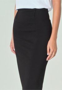 Falda lápiz negra con textura suave, cintura alta y discretos bolsillos laterales. Presenta un diseño entallado que se estrecha hacia el dobladillo.