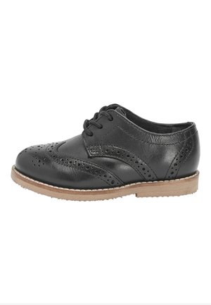 Chaussure brogues en cuir noir avec perforations en forme d'aile, fermeture à lacets et semelle marron clair, vue de côté extérieur.