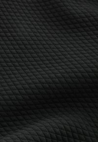 Černá texturovaná látka s diamantovým prošívaným vzorem, zobrazující měkký, tkaný vzhled s mírným leskem a hloubkou.