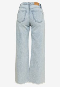 Svetle modré džíny s širokými nohavicemi a vysokým pasem, dvěma zadními kapsami a neupraveným lemem. Na pasu je vyzna�čená kožená nášivka s logem značky.