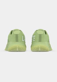 Πράσινα αθλητικά παπούτσια με υφή στο πάνω μέρος, λευκή σήμανση και λαστιχένια σόλα με μοτίβο ζιγκ ζαγκ. Εμφανίζεται από πίσω.