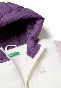 Pikowana kurtka z fioletowym kapturem, białą częścią i jasnoróżowymi akcentami. Posiada zamek błyskawiczny i wyszywane logo z przodu.