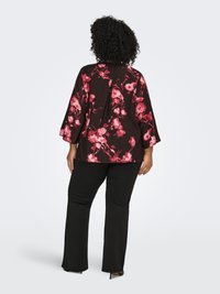 Black floral blouse with pink watercolor-style flowers, featuring three-quarter sleeves, paired with black pants, smooth fabric and straight fit.