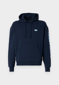 Sudadera azul marino de algodón, con un bolsillo frontal, capucha ajustable con cordón y "TOMMY JEANS" impreso en blanco en la manga.