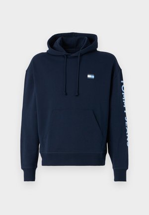 Dunkelblaues Hoodie aus Baumwolle, mit einer Vordertasche, verstellbarem Kordelzug und "TOMMY JEANS" in Weiß auf dem Ärmel bedruckt.